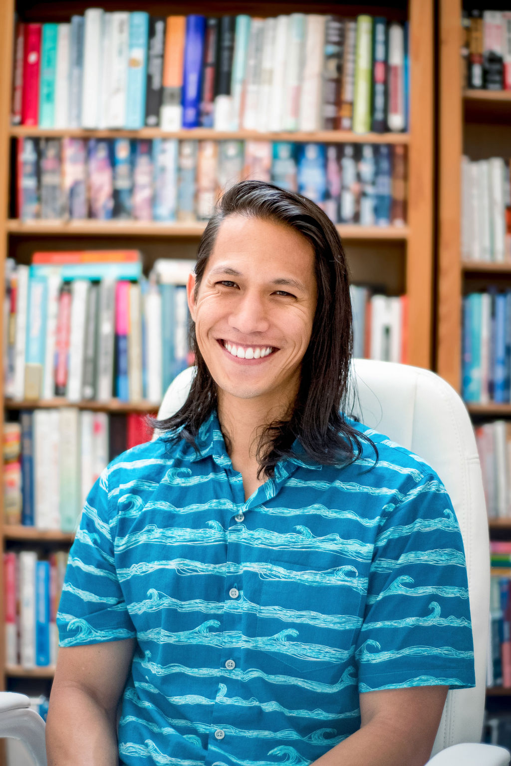 Colton Kekoa Neves smiling in front of a bookcase